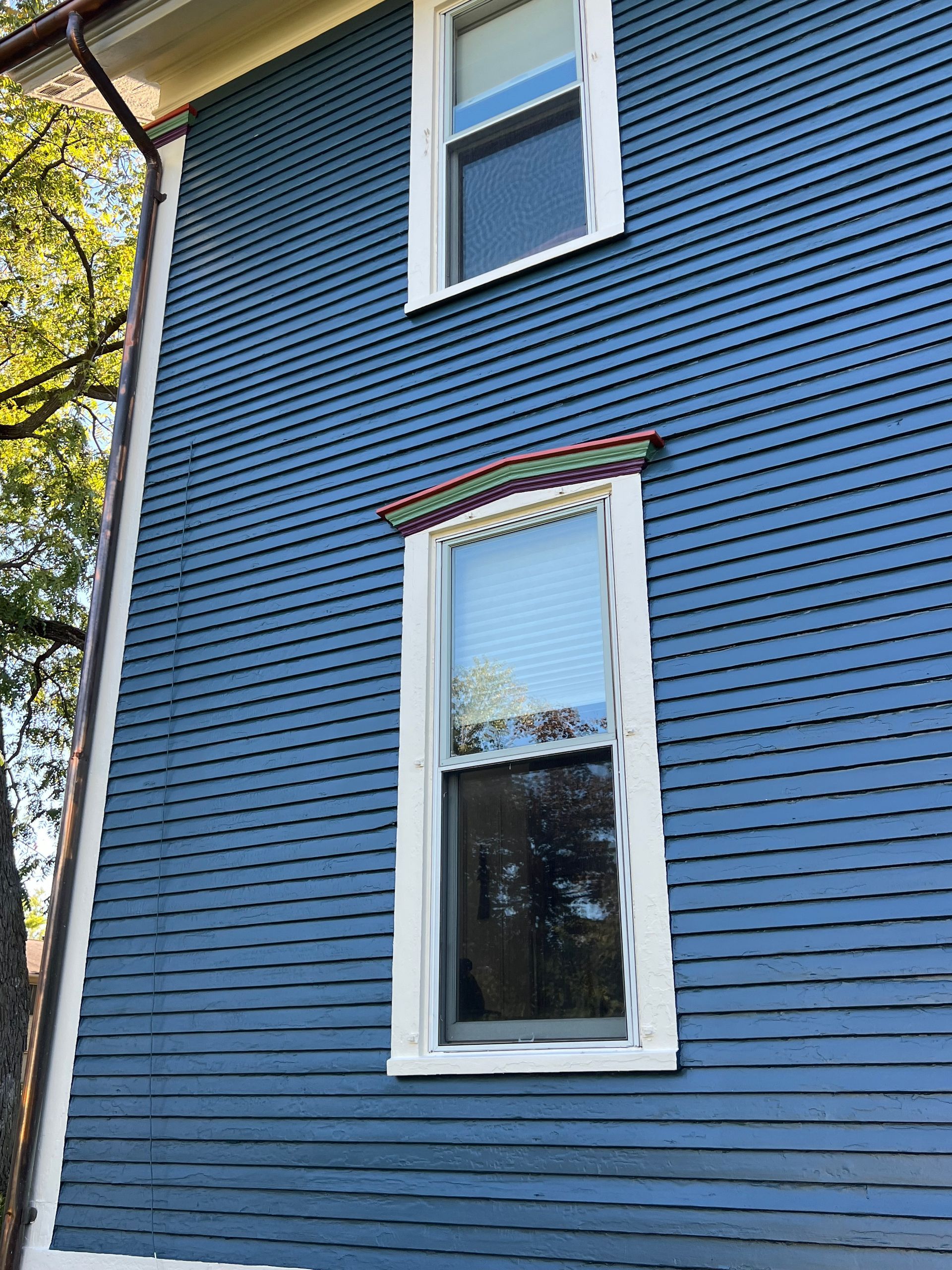 A blue house with a white window and a rainbow trim.