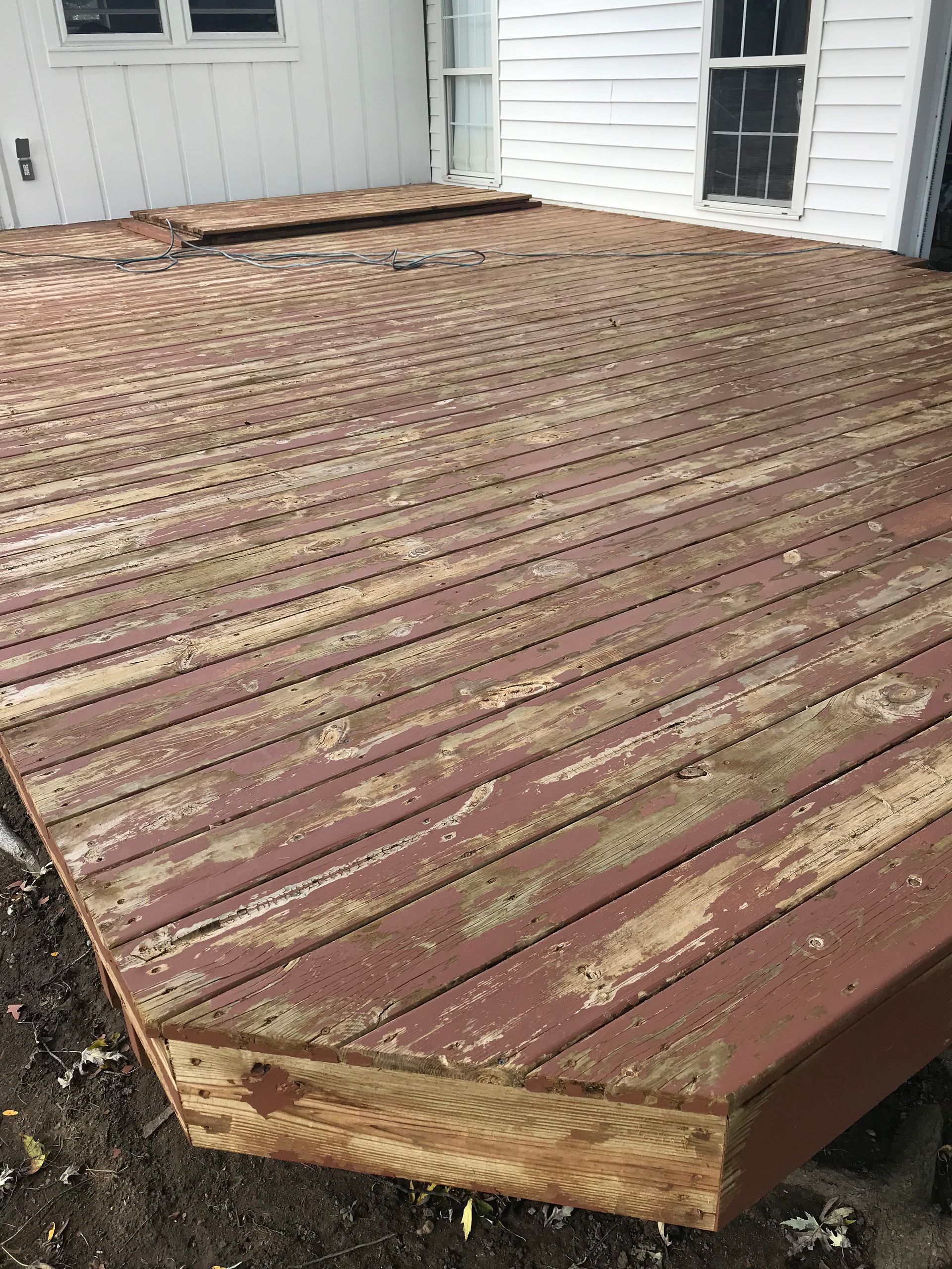 A wooden deck is sitting in front of a white house.