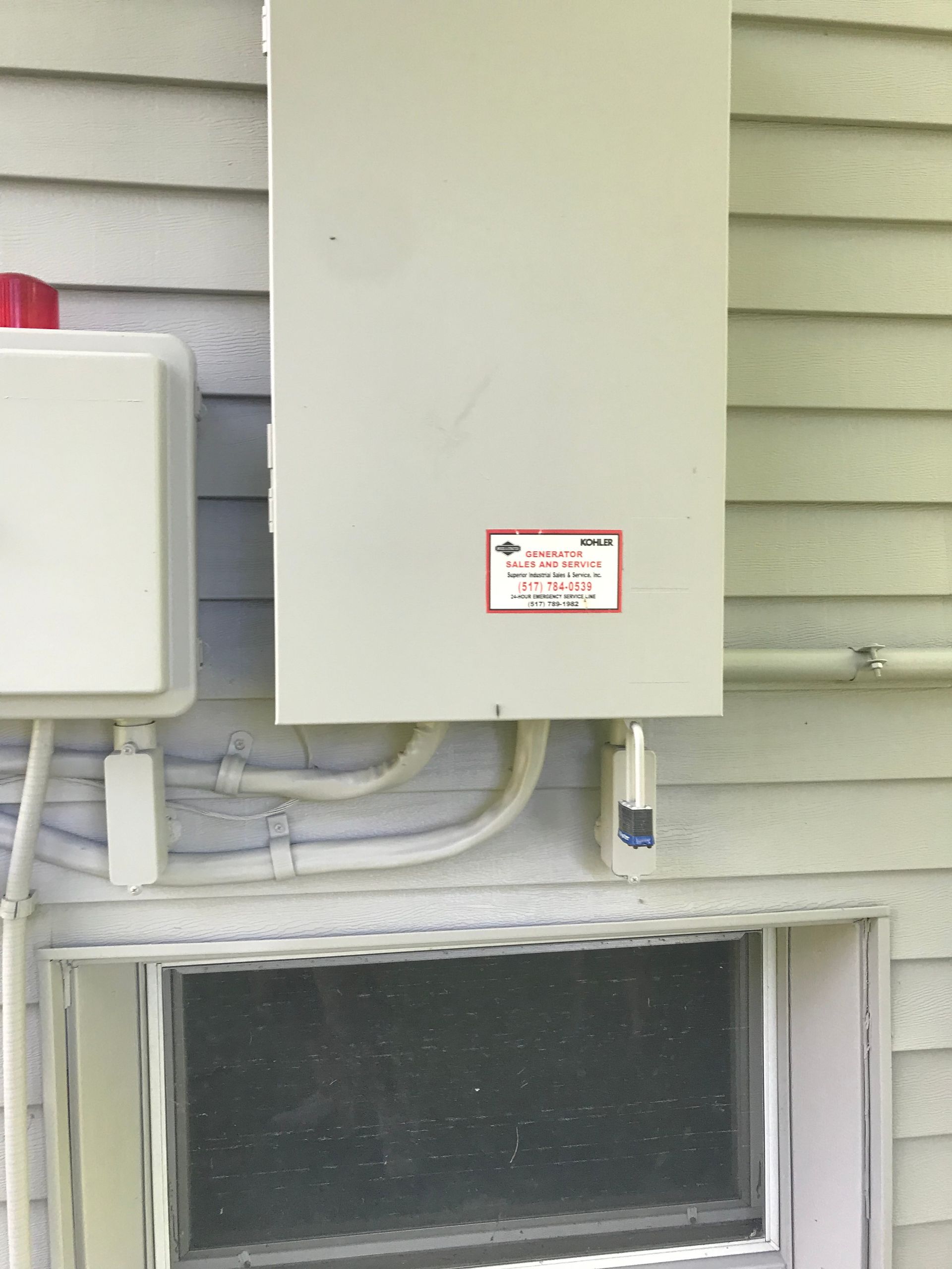 A white box on the side of a house next to a window