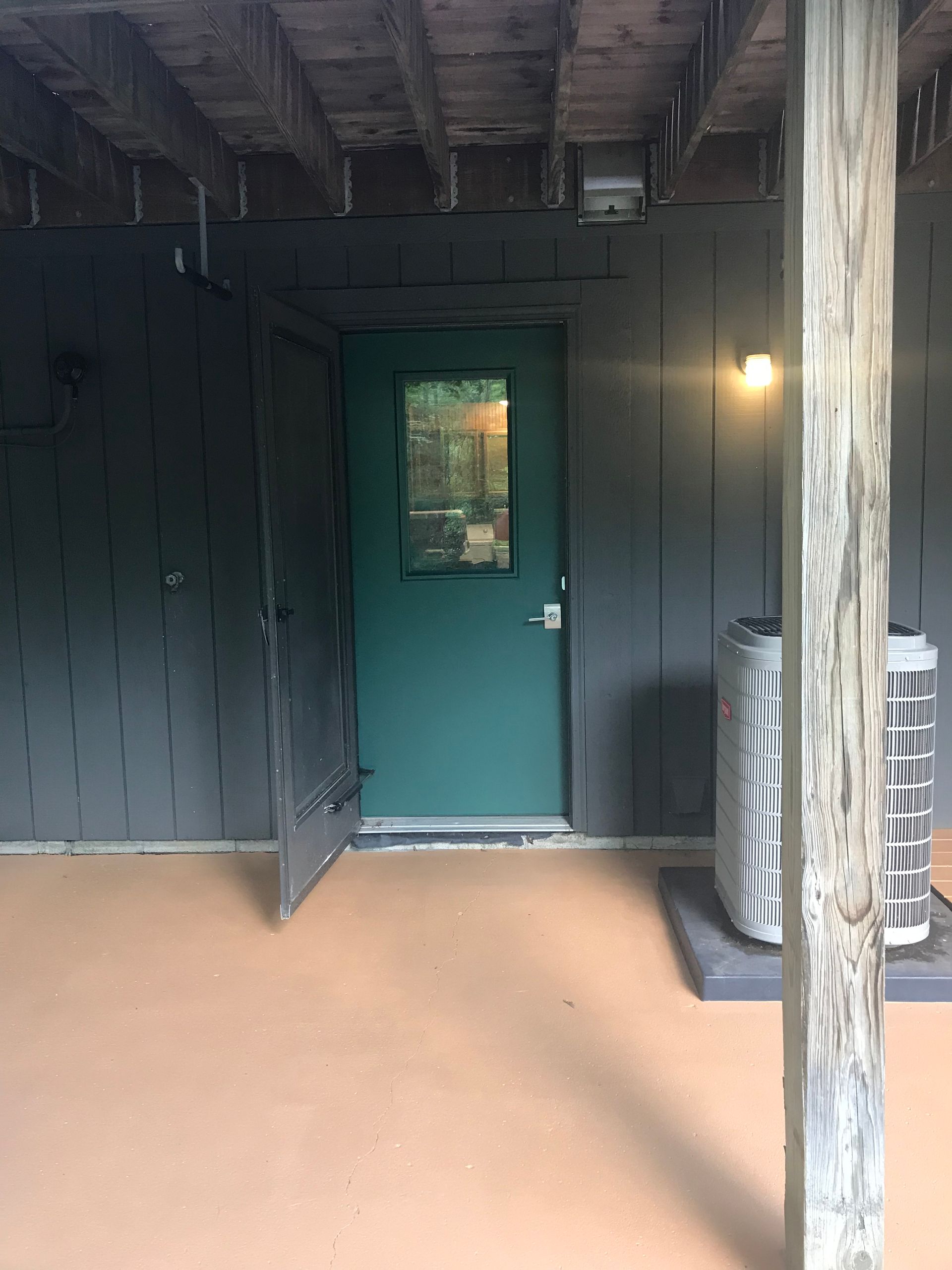 A green door is open on a porch next to a heater.