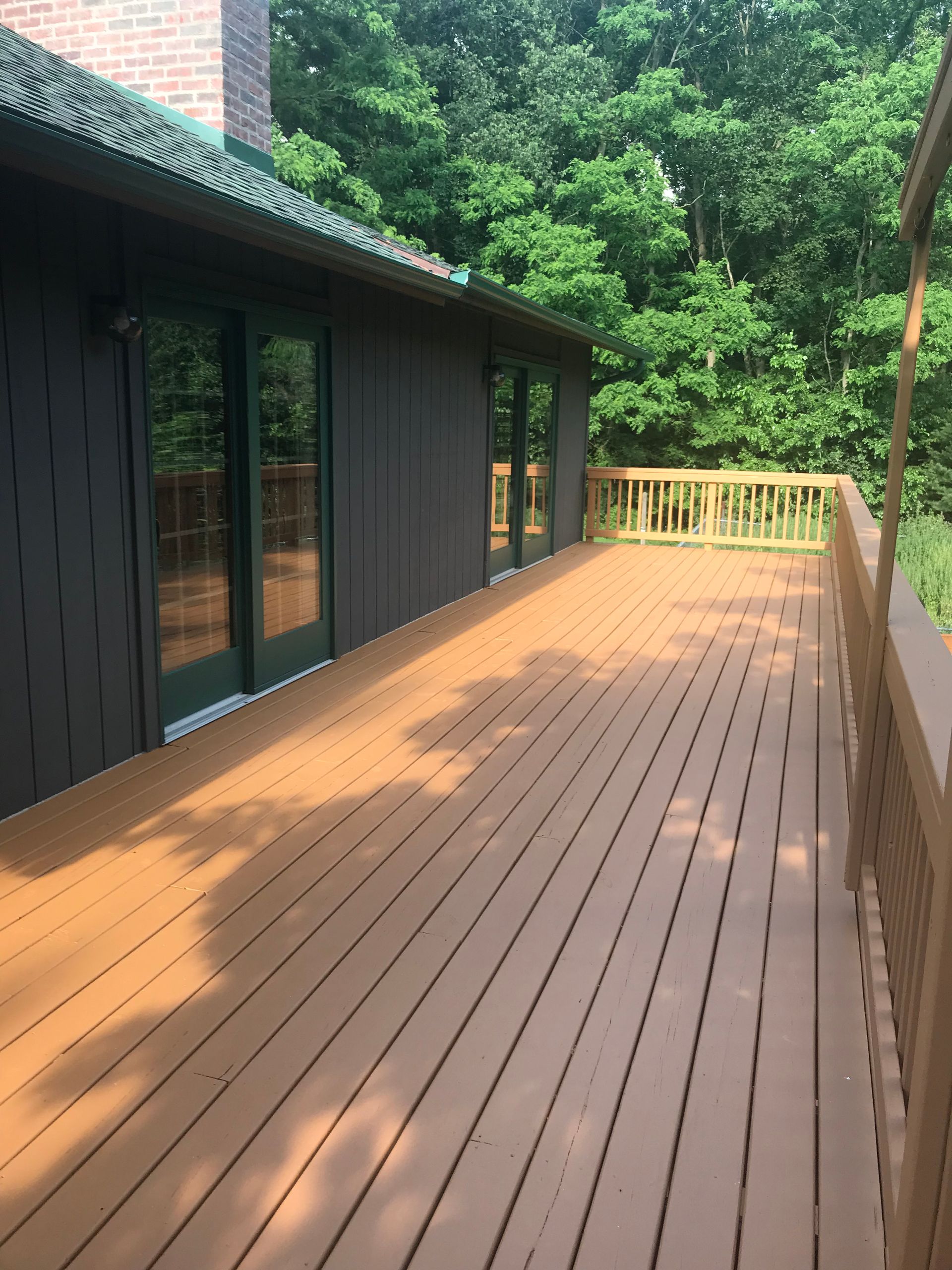 A large wooden deck with a black building in the background.