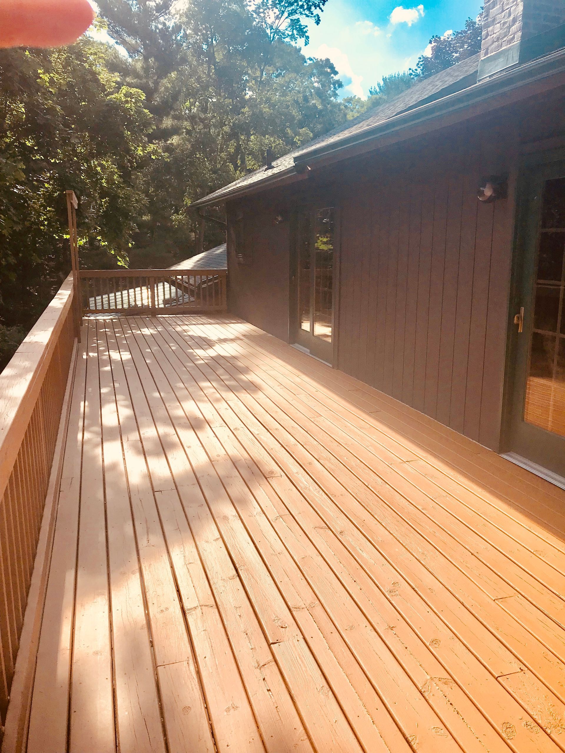 A person is holding a wooden deck in front of a house.