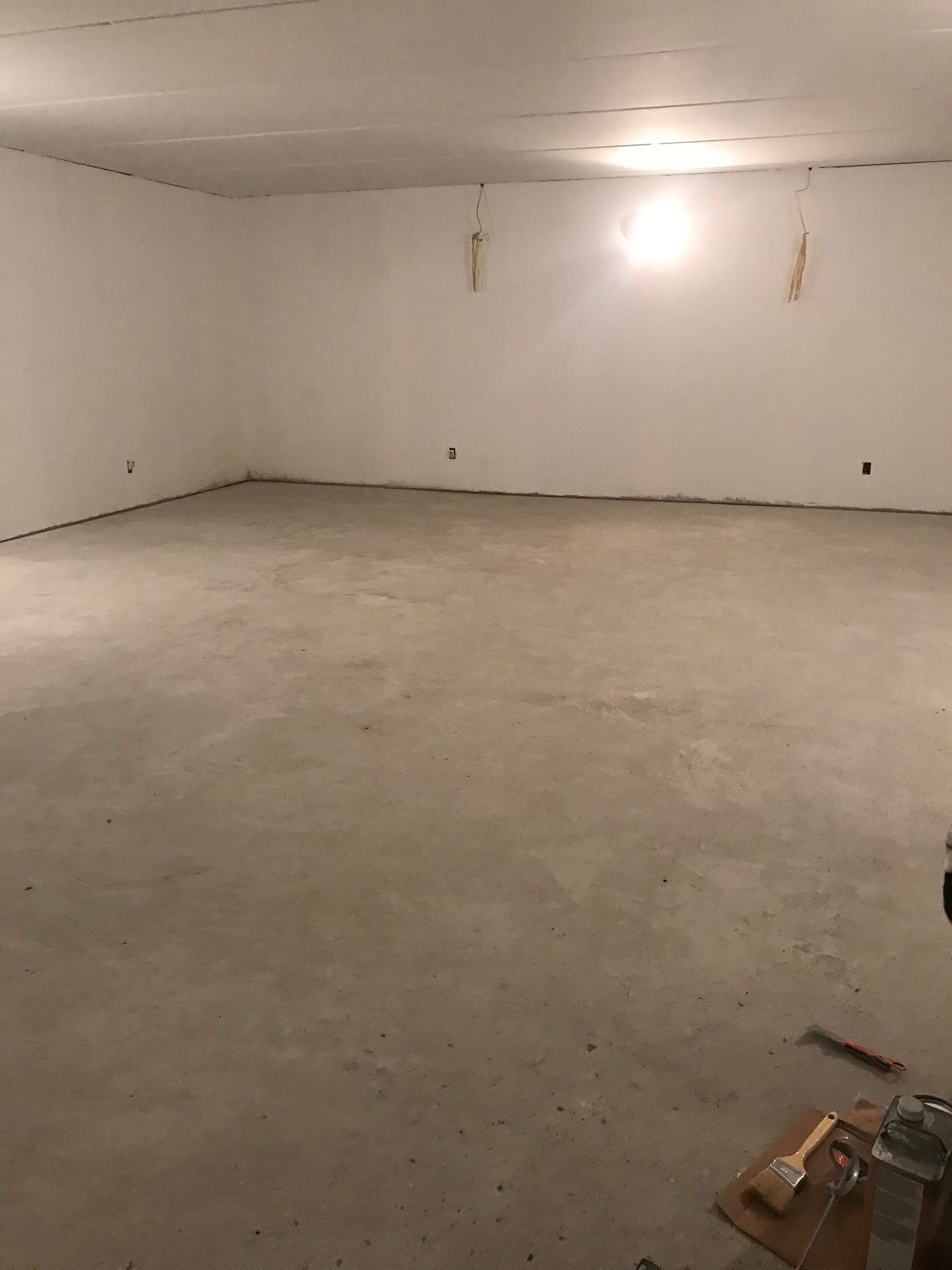 A large empty room with a concrete floor and white walls.