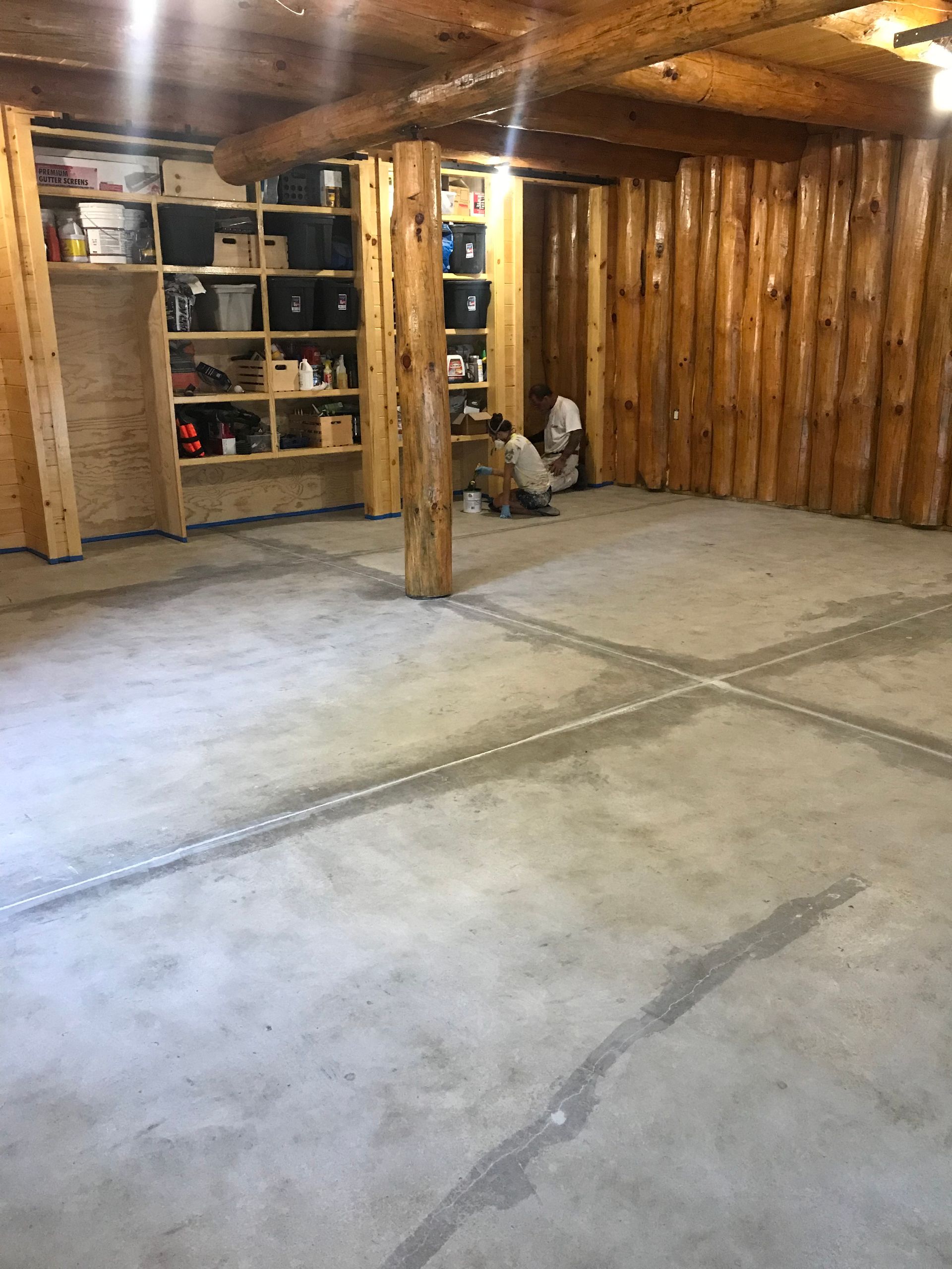 A large room with a concrete floor and wooden shelves.