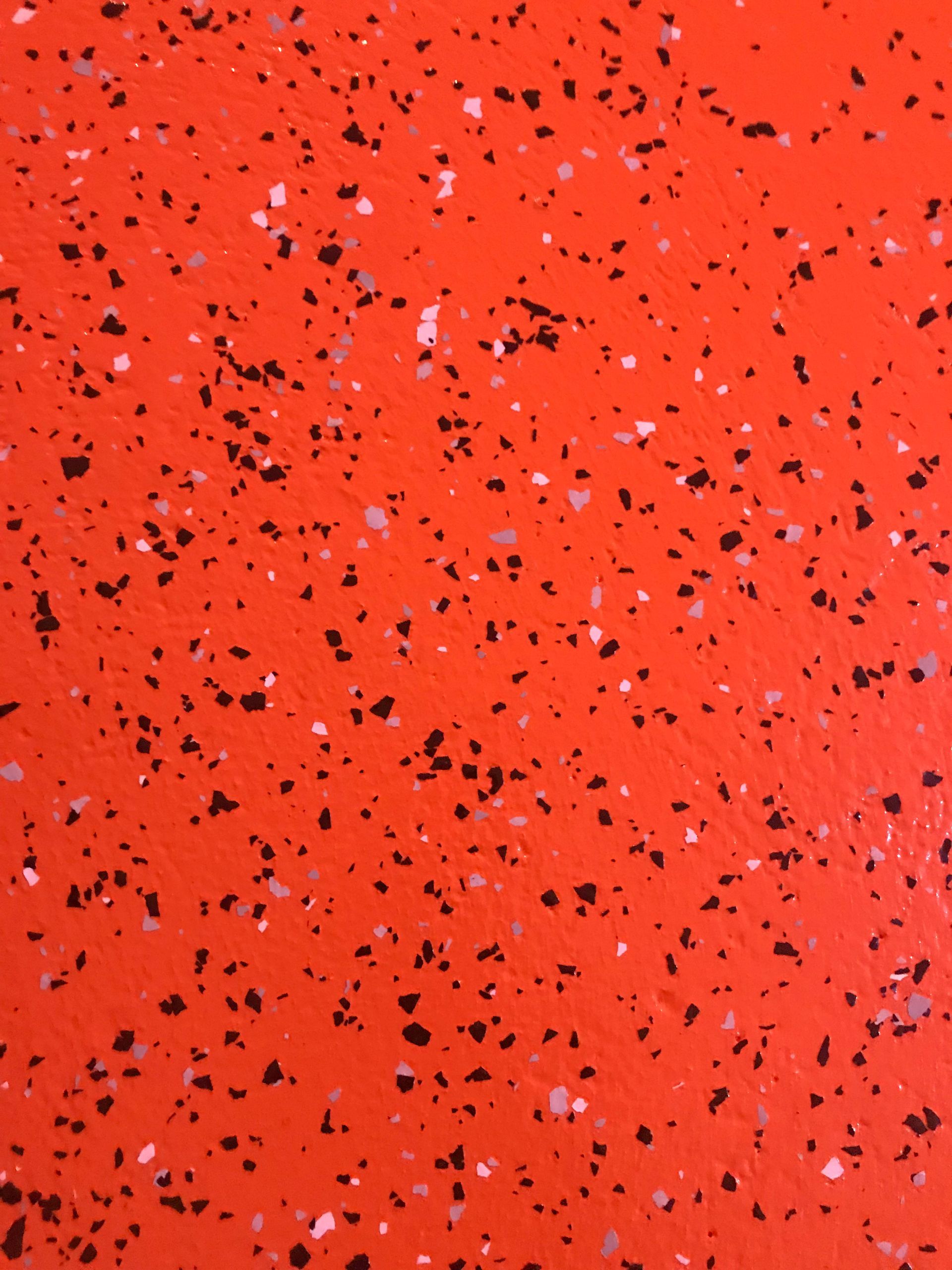 A close up of a red surface with black and white spots