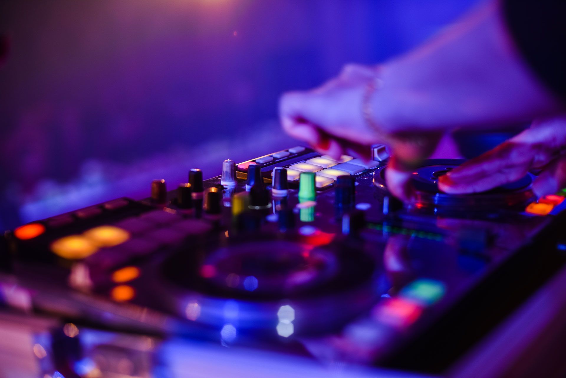 A four-piece band performs on a stage with large windows, warm lighting, and music equipment in an industrial-style room.