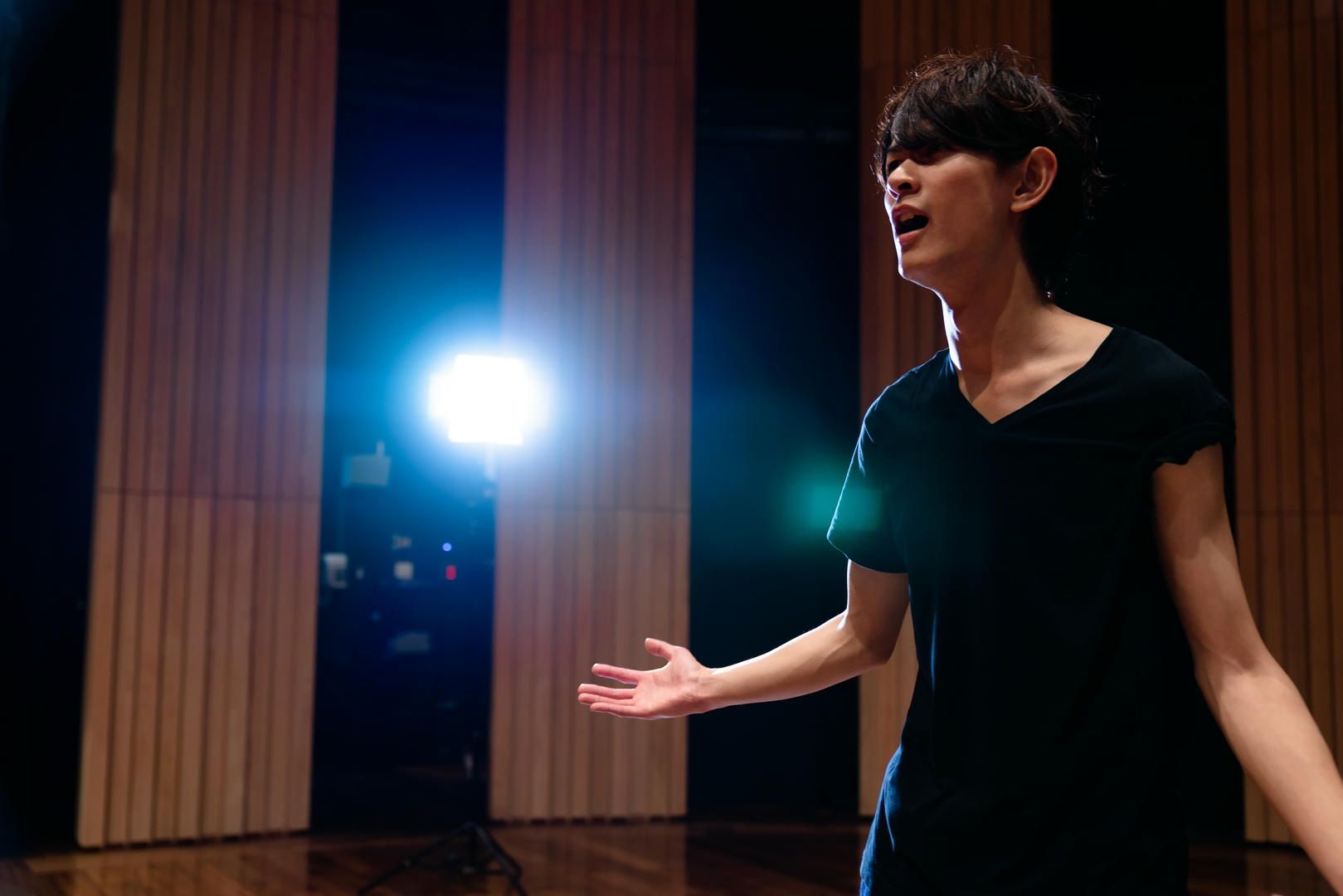 A woman is singing on a stage in front of a light.