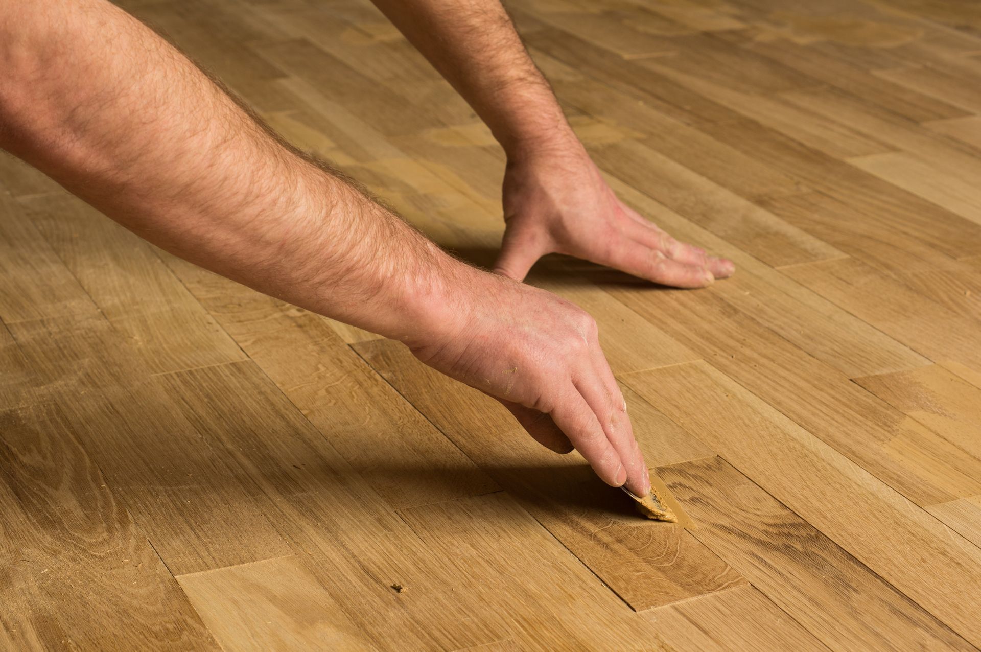 Hands touching and inspecting hardwood floorboards