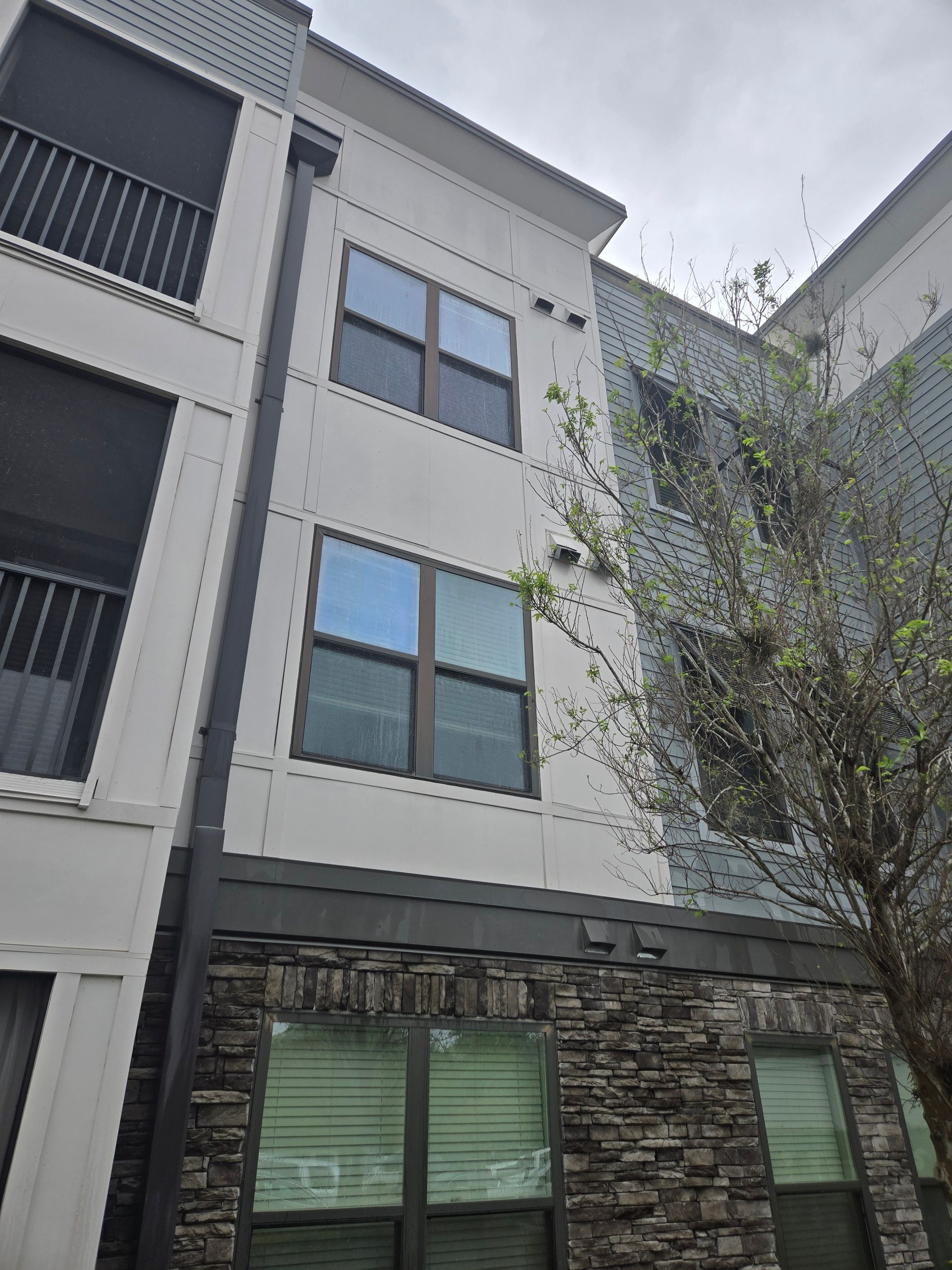 Multi-story apartment building with stone facade on bottom, windows, and balconies.