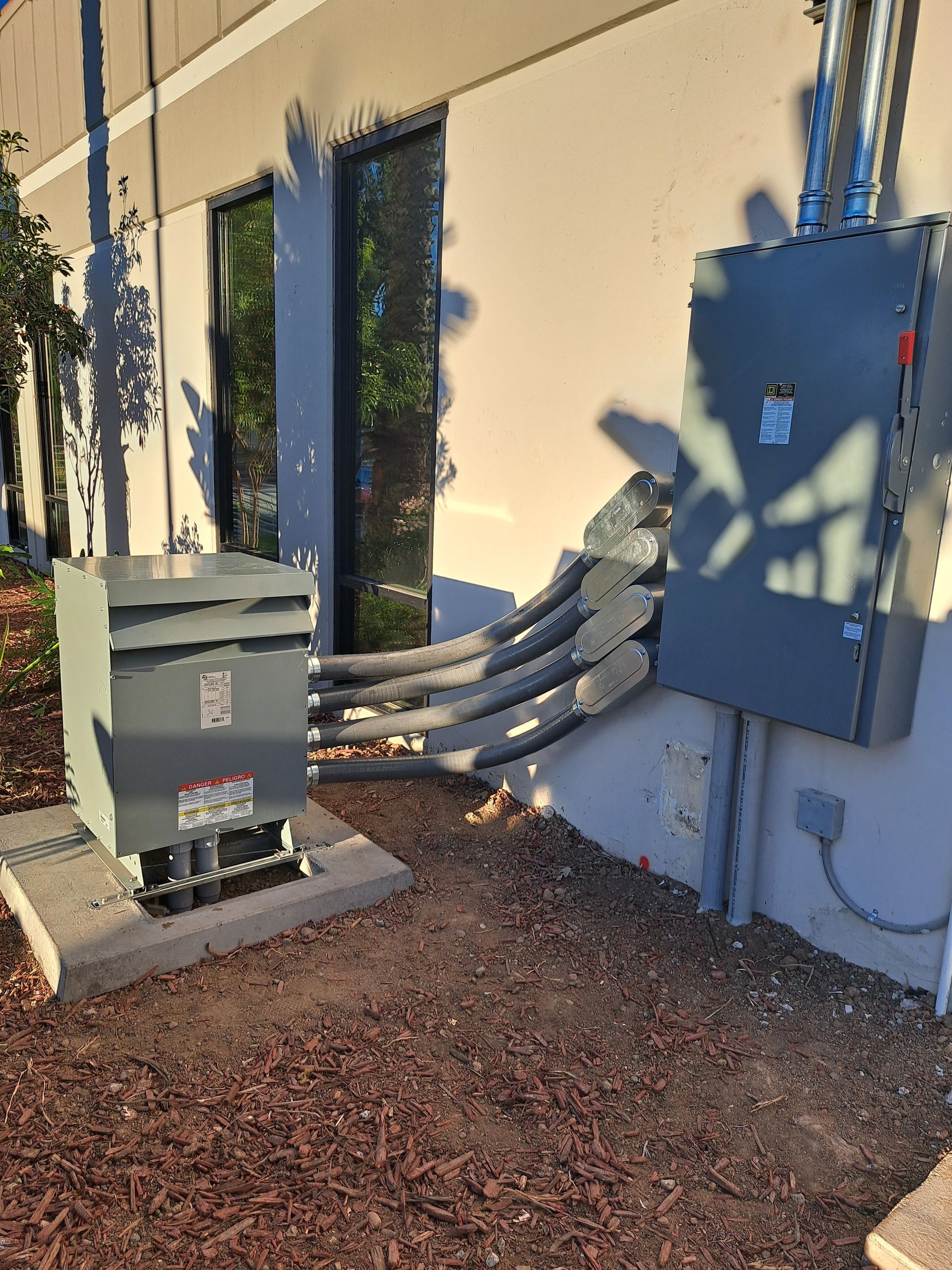 A transformer and a box are sitting outside of a building.