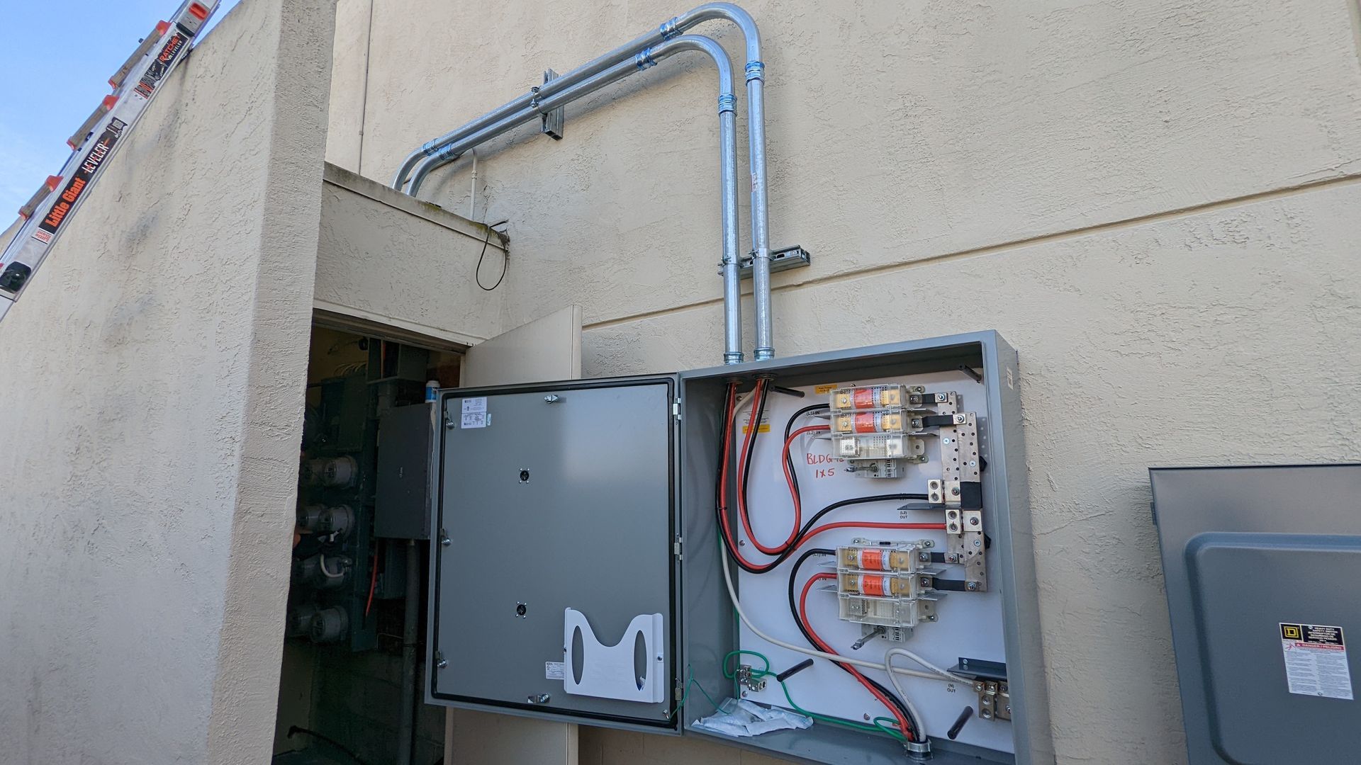 A large electrical box is attached to the side of a building.