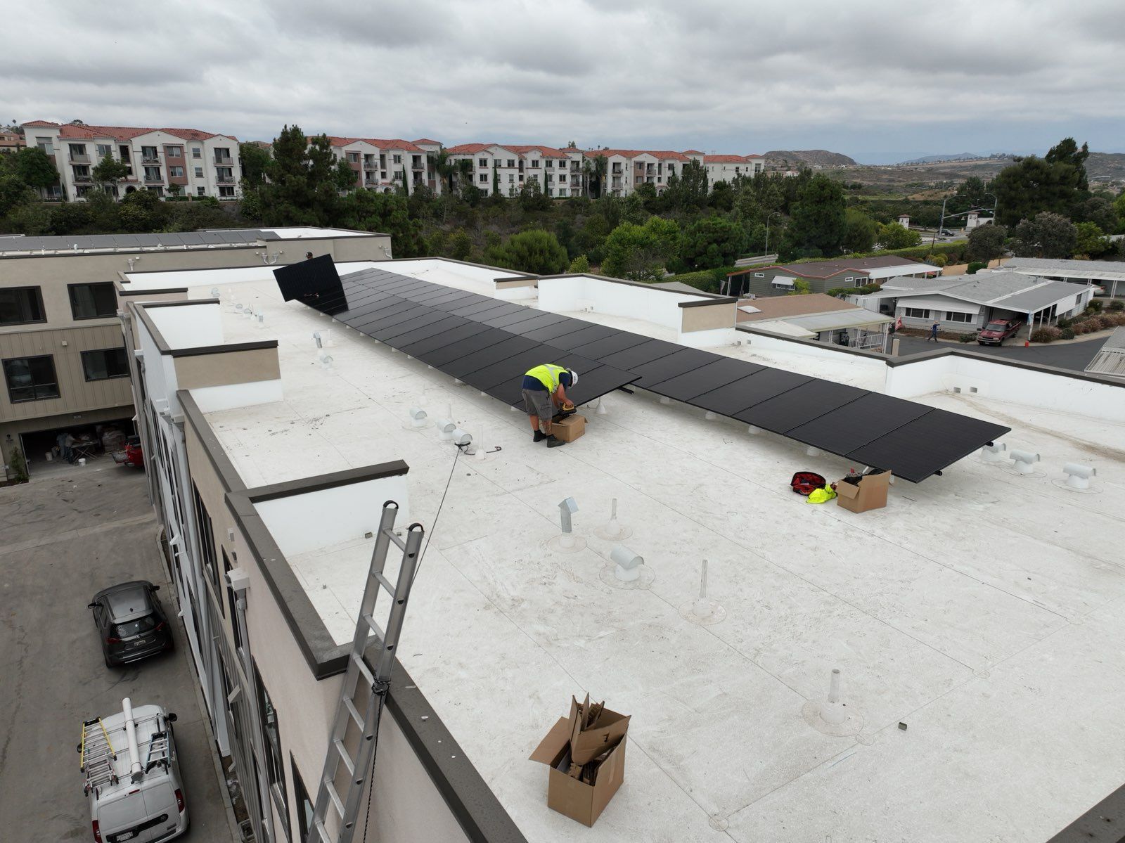 A man is installing solar panels on the roof of a building