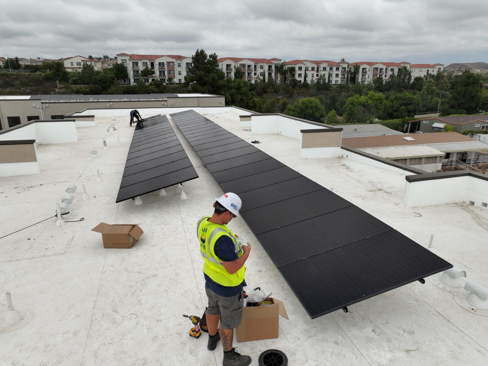 A man is installing solar panels on the roof of a building.