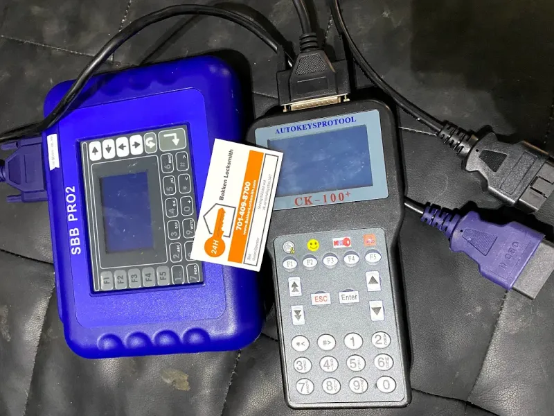 Two blue and gray automotive diagnostic tools, with cables and a key card.
