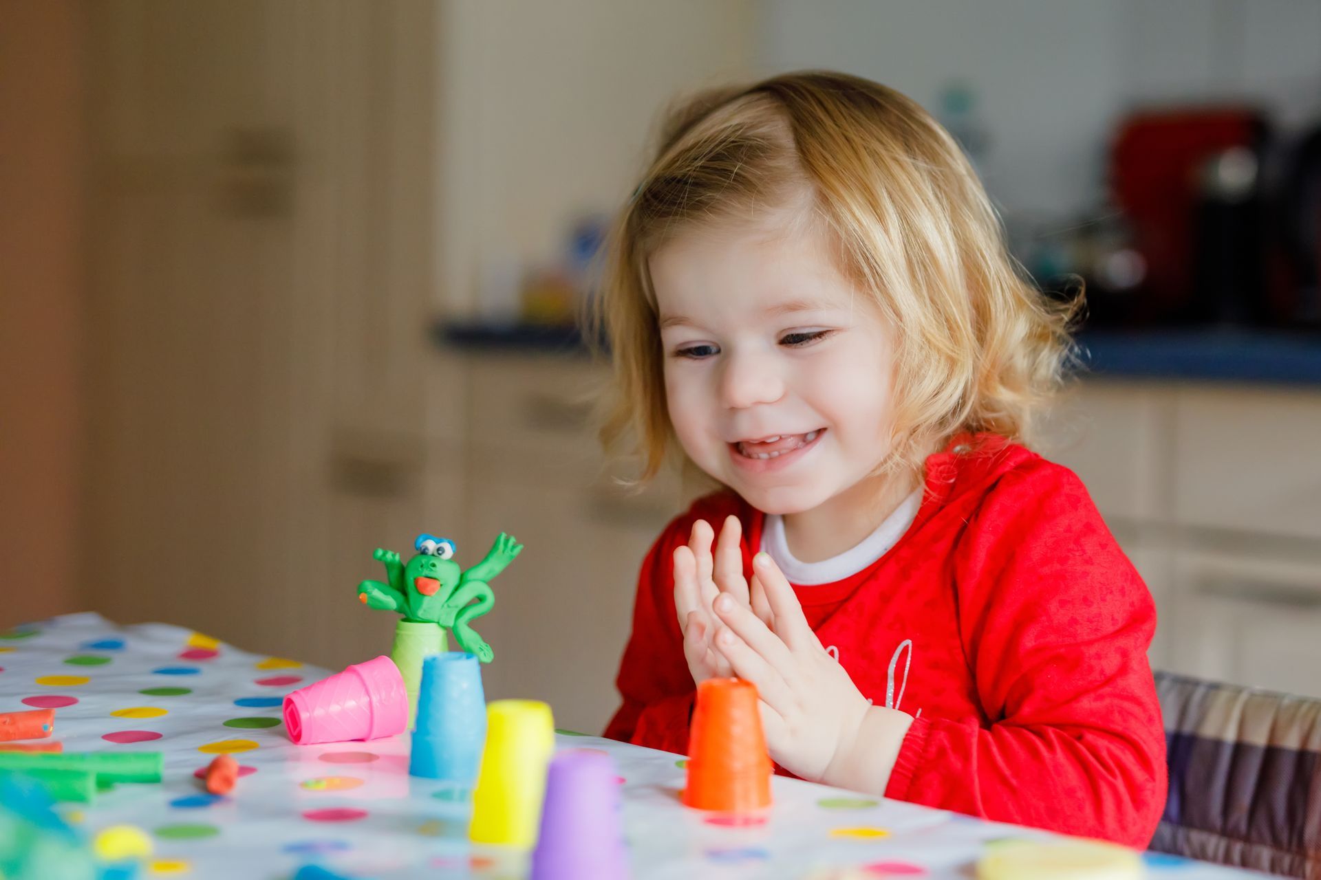 A little girl is sitting at a table playing with toys.