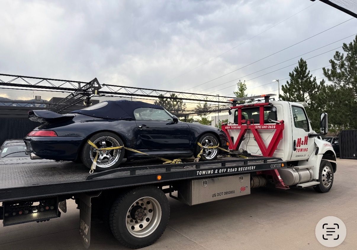 Blue convertible Porsche on a tow truck.