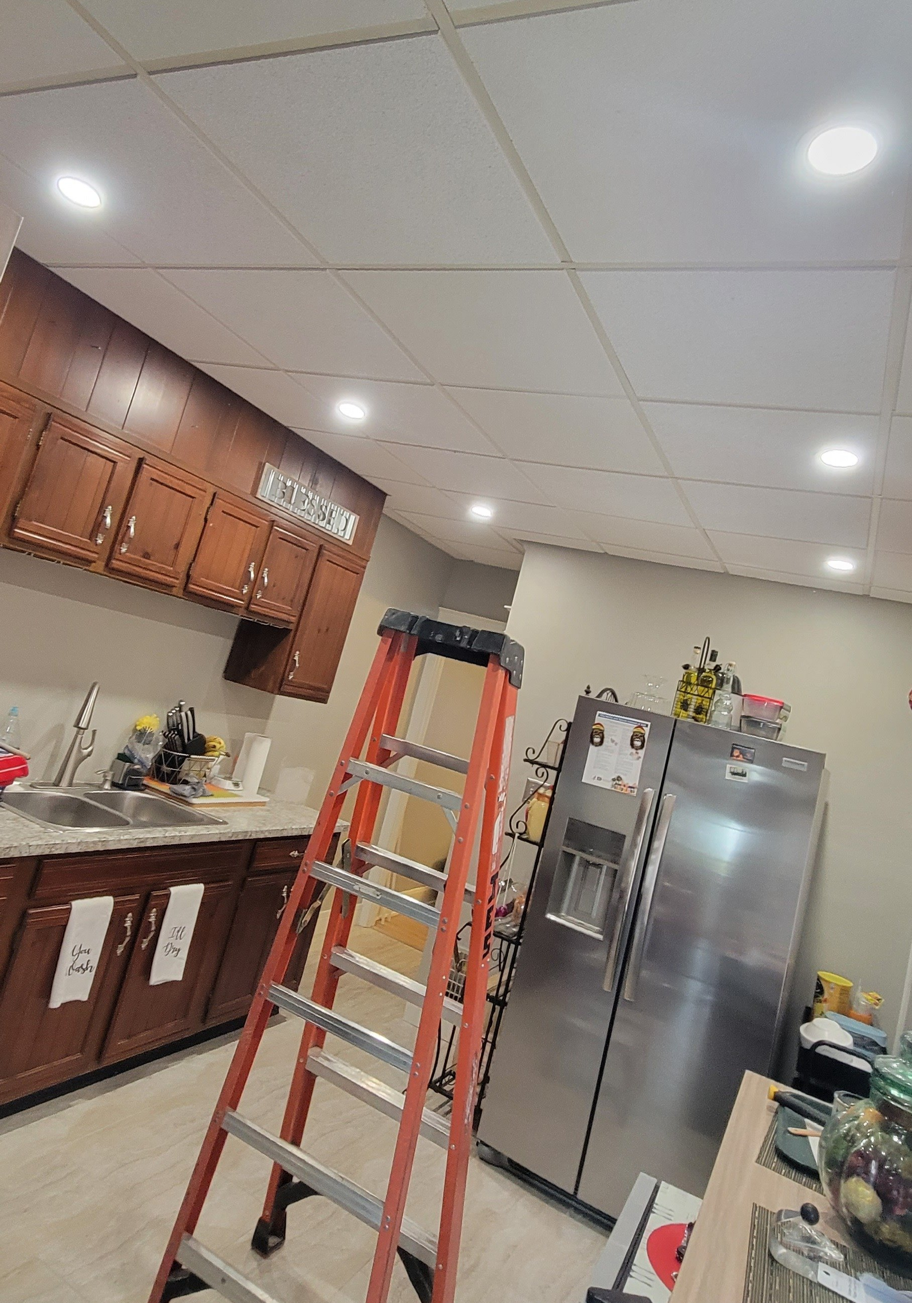 a kitchen with a ladder next to a refrigerator .
