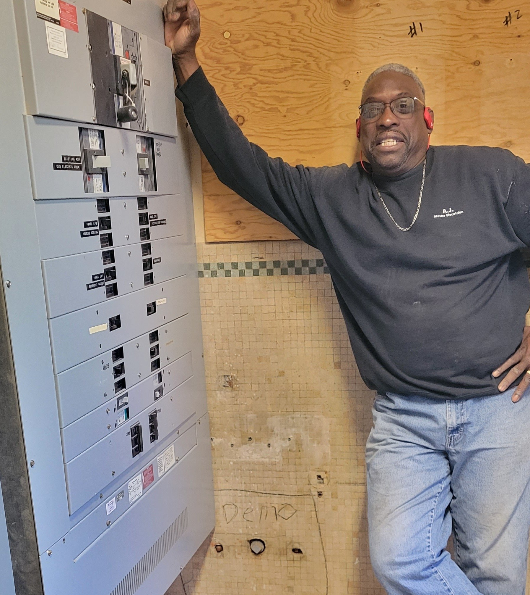 a man in a black shirt is leaning against a wall with a large panel board