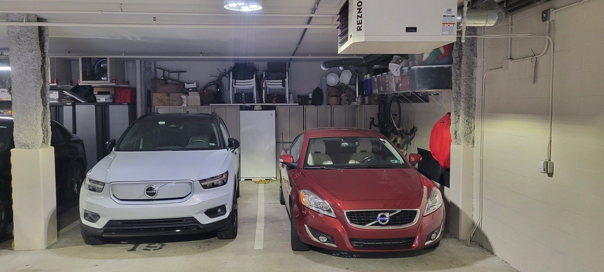 two cars are parked in a garage next to each other .