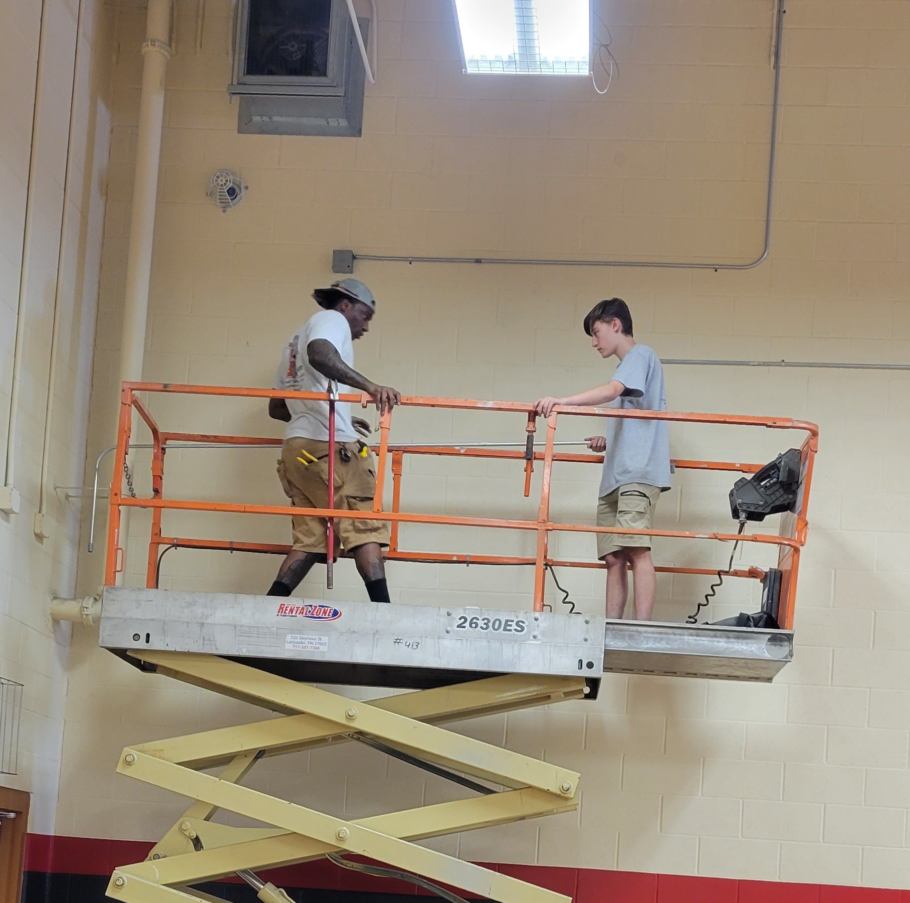two men are working on a scissor lift which says jlg on it
