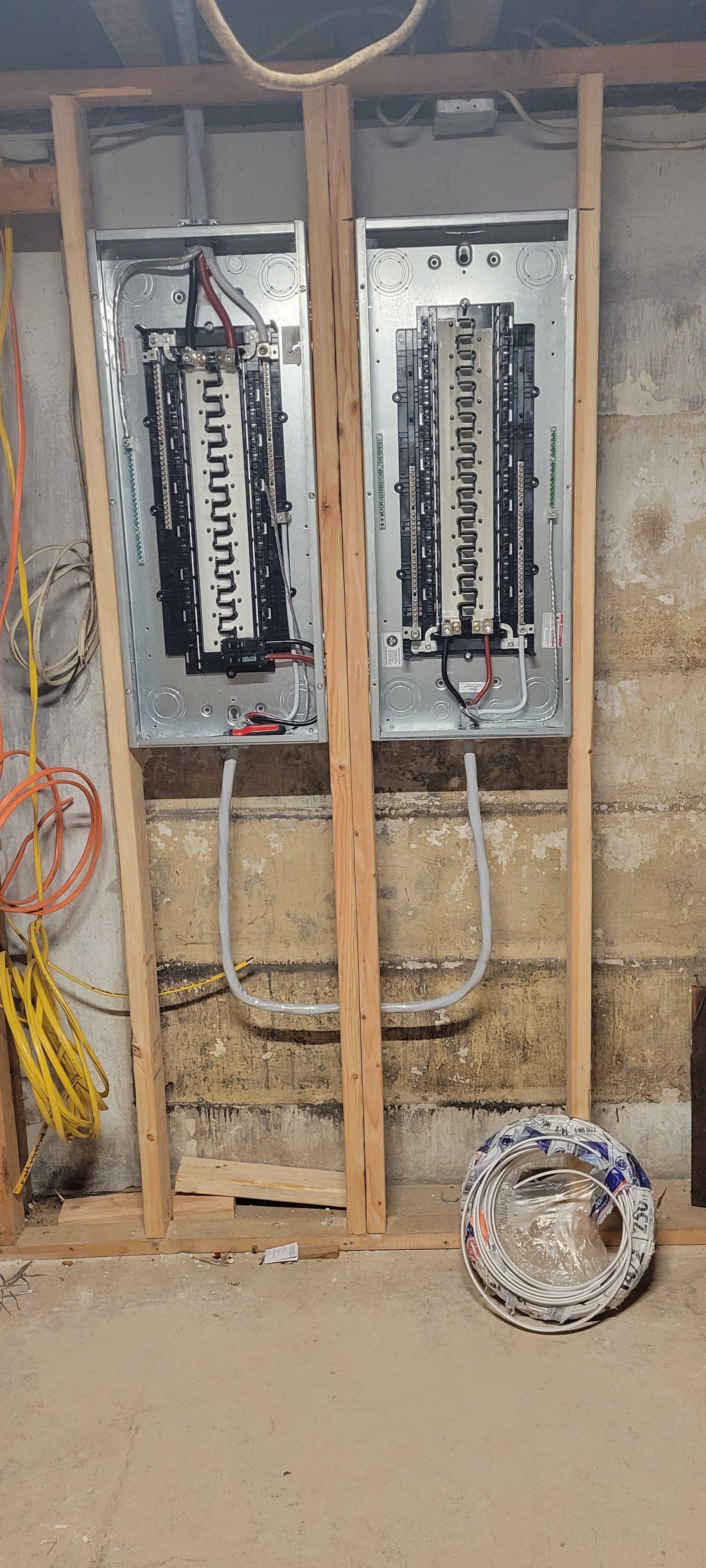 two electrical panels are hanging on a wall in a basement .