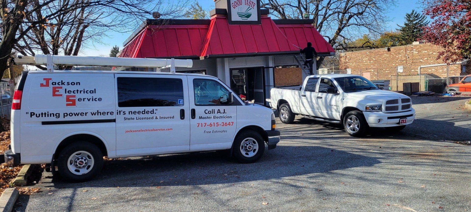 two vans and a truck are parked in front of a fast food restaurant .