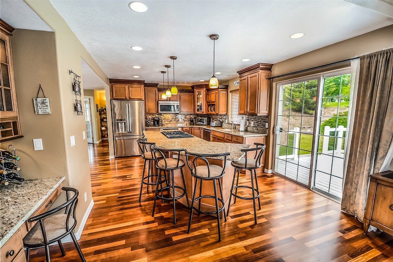 a kitchen with hardwood floors , stainless steel appliances and a large island .
