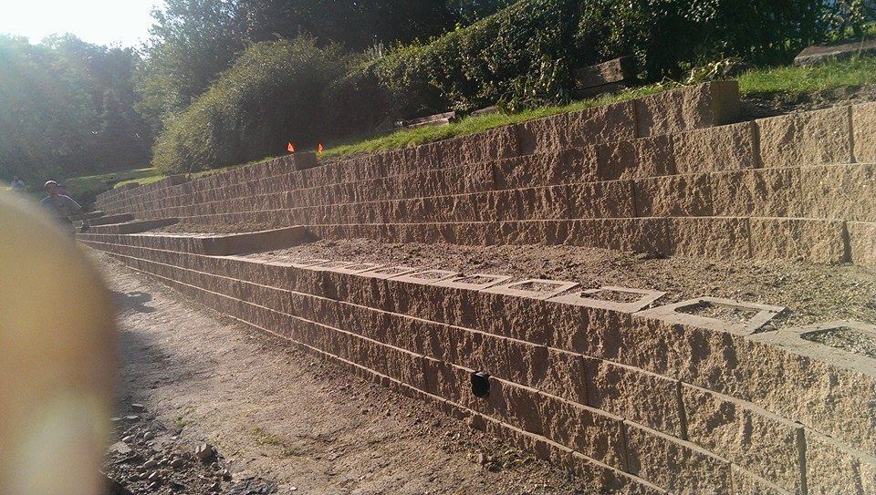 A brick wall is being built on a dirt road.