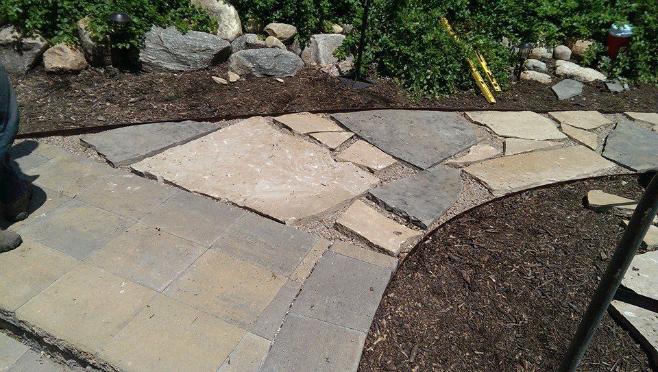 A person is standing on a stone walkway in a garden