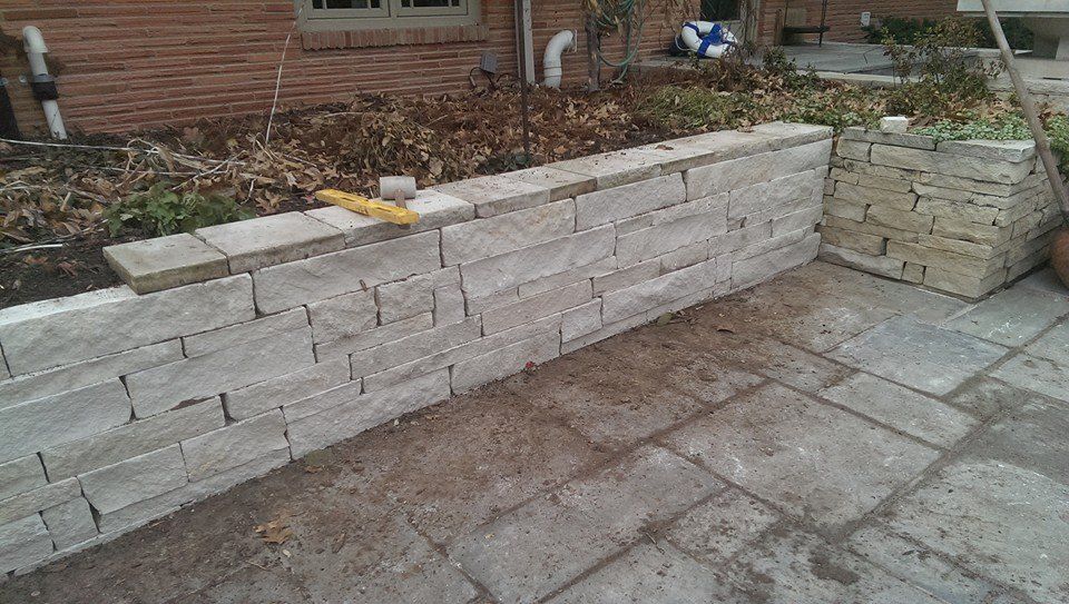 A brick wall is being built next to a brick patio.