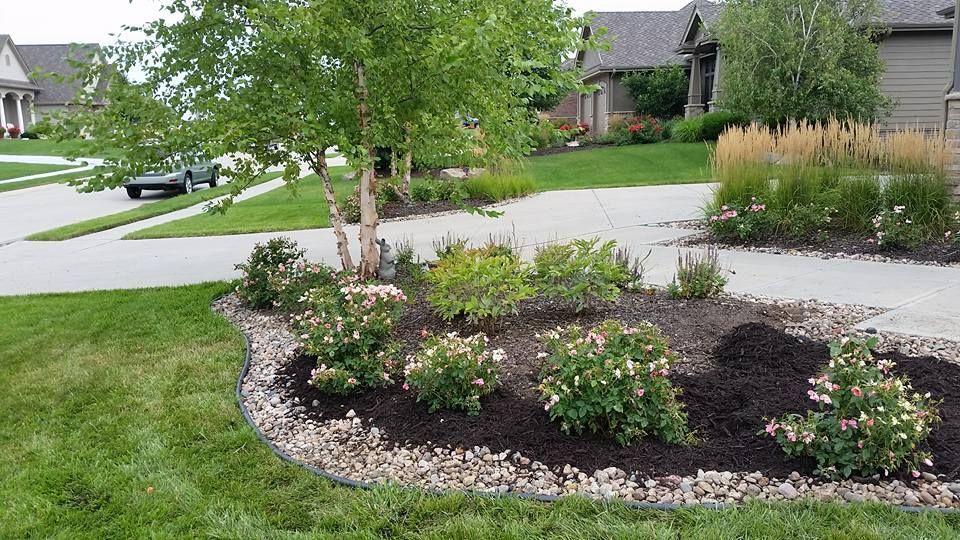 A lush green lawn in front of a house with a car parked in the driveway.