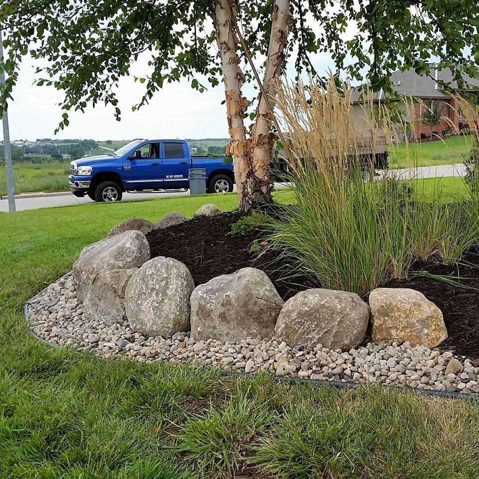A blue truck is parked next to a rock garden