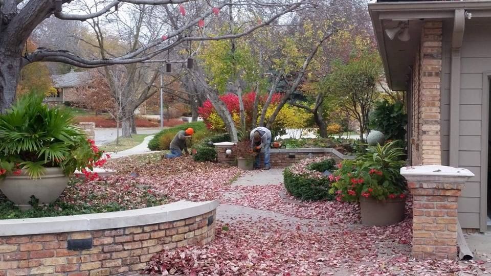 A man is raking leaves in front of a house.