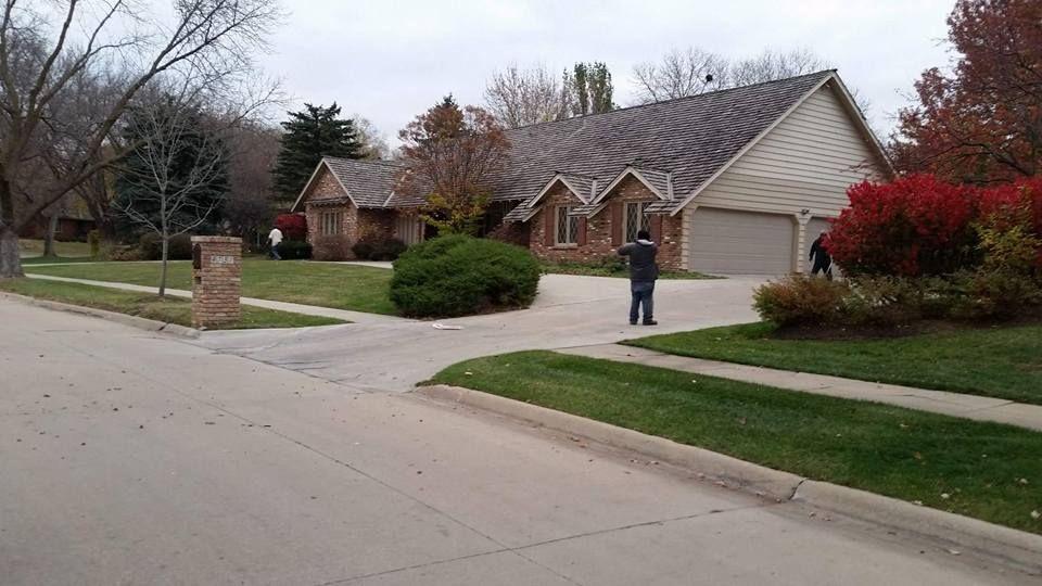 A man is standing in front of a house in a residential neighborhood.