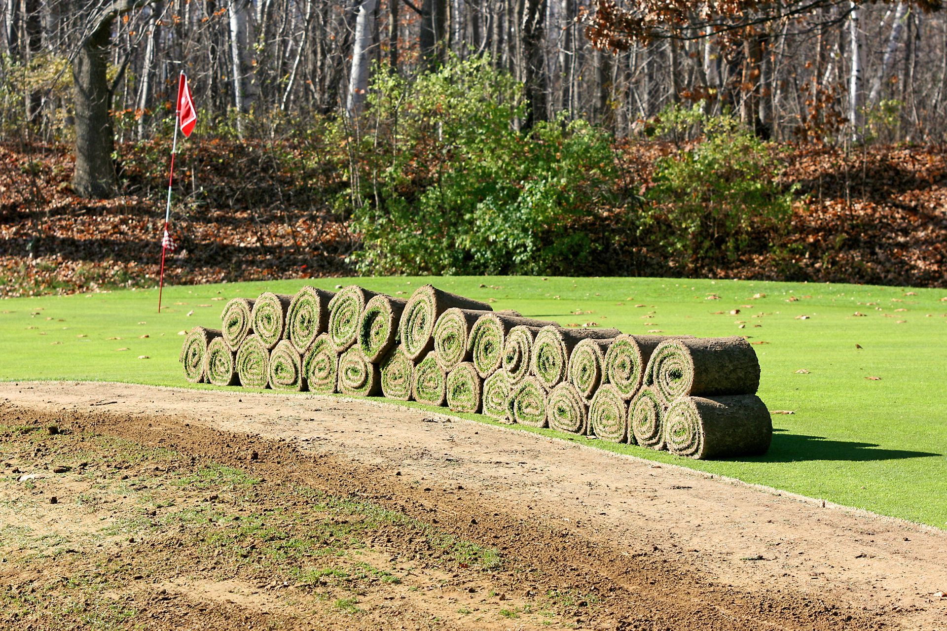 A bunch of rolls of grass are stacked on top of each other on a golf course.