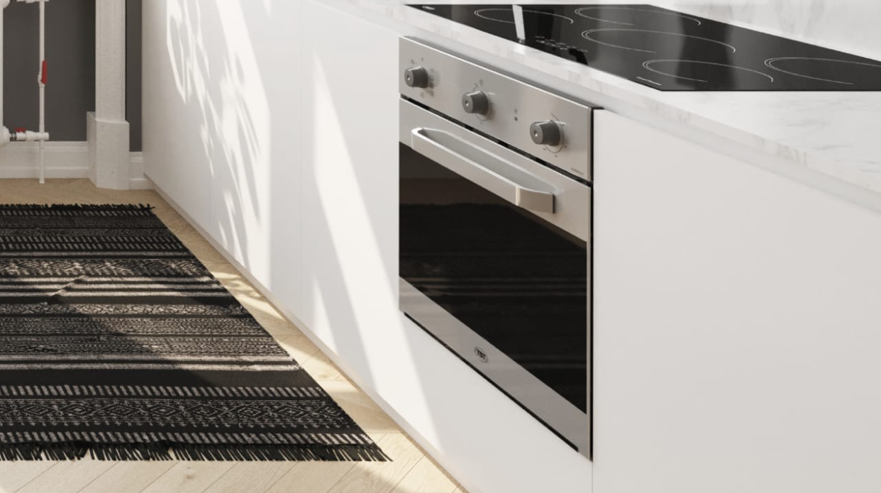 Una cocina con un horno de leña y una alfombra en el suelo.