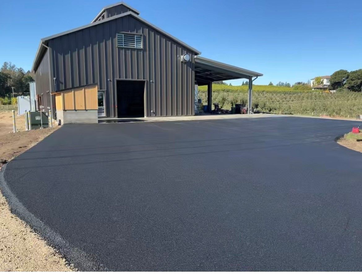 A large barn with a driveway in front of it.