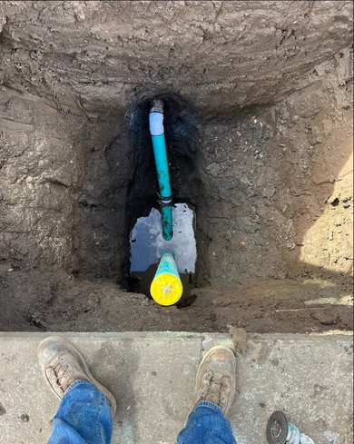 A person is standing next to a shovel in a hole in the ground.