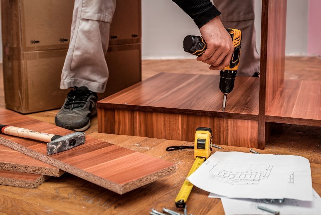 A man is using a drill to drill a hole in a piece of wood.