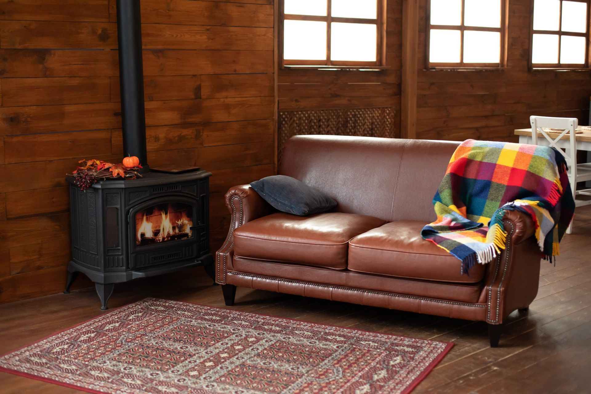 Cozy living room with a lit fireplace, brown leather couch, and colorful blanket.