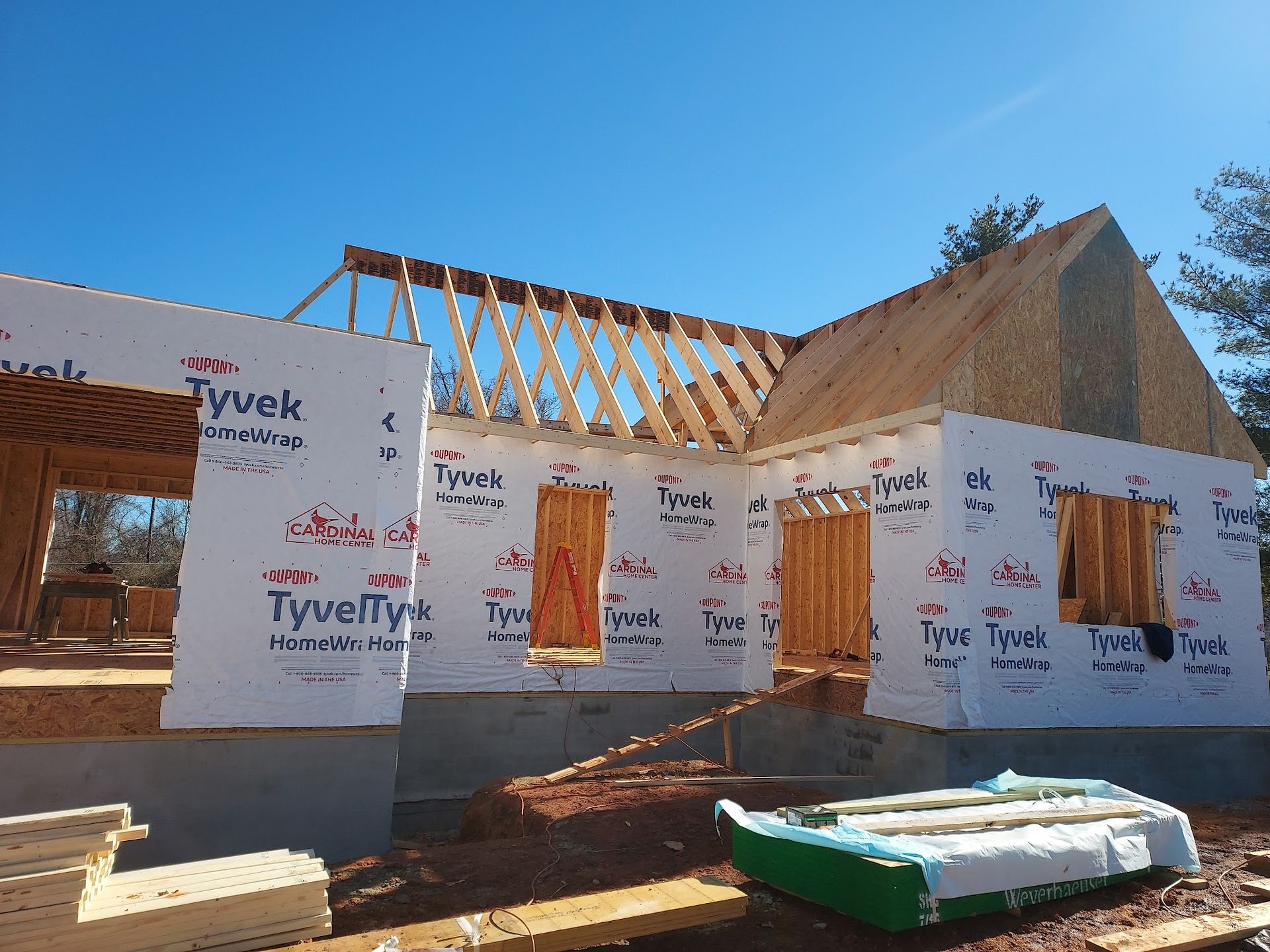 Construction of a house: wooden frame, Tyvek wrap, blue sky.