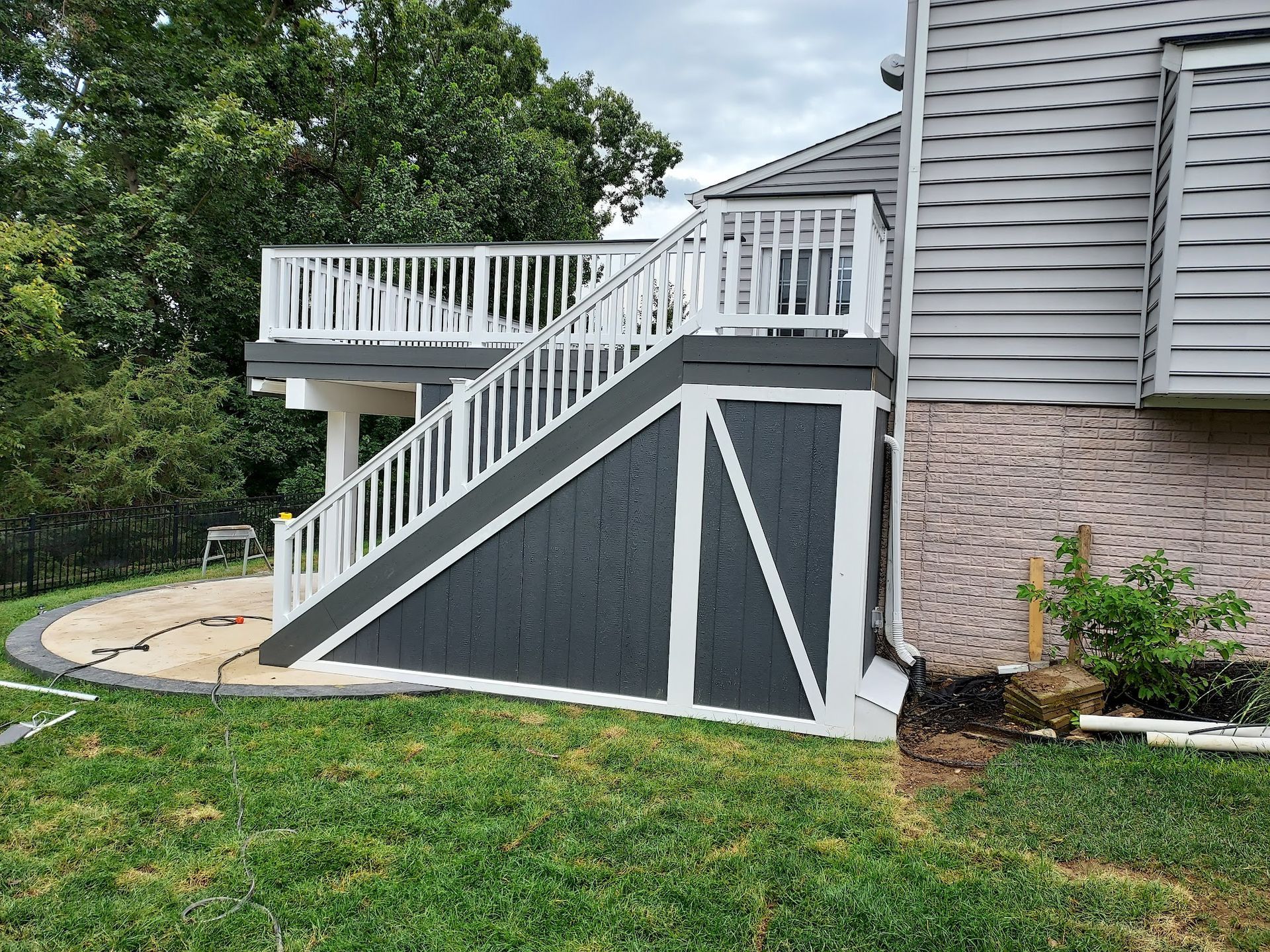Dark gray deck with white trim and steps, attached to a house with gray siding.