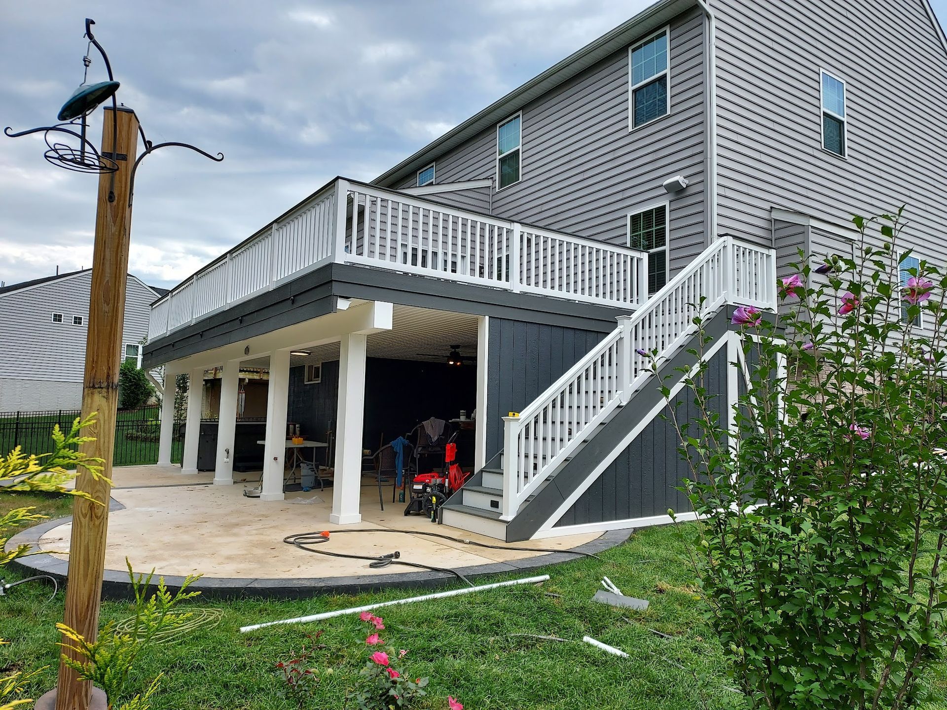 Deck extension with white railings and gray siding on a two-story house.