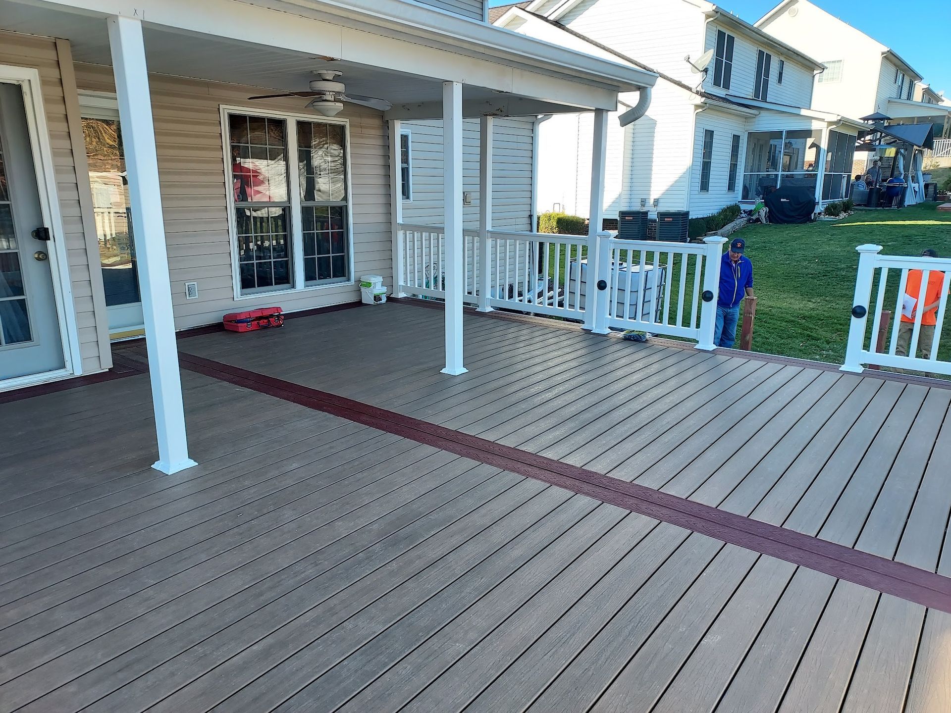 Composite deck with white railing and support posts, connecting to a house with beige siding.
