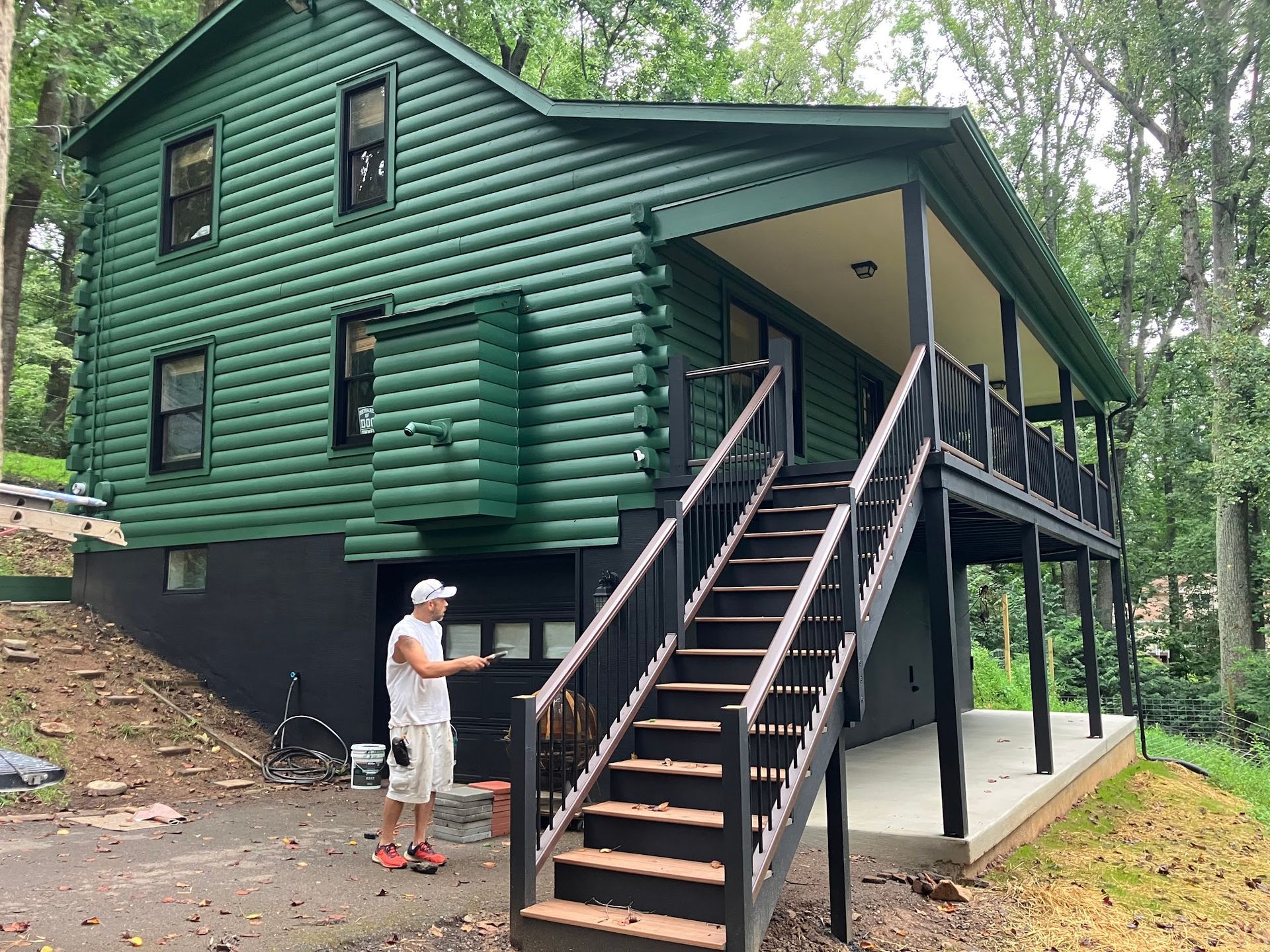 Green cabin with black trim, a man stands by a stairway.