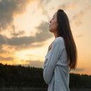 Woman in a white tank top stretching outdoors by a calm lake
