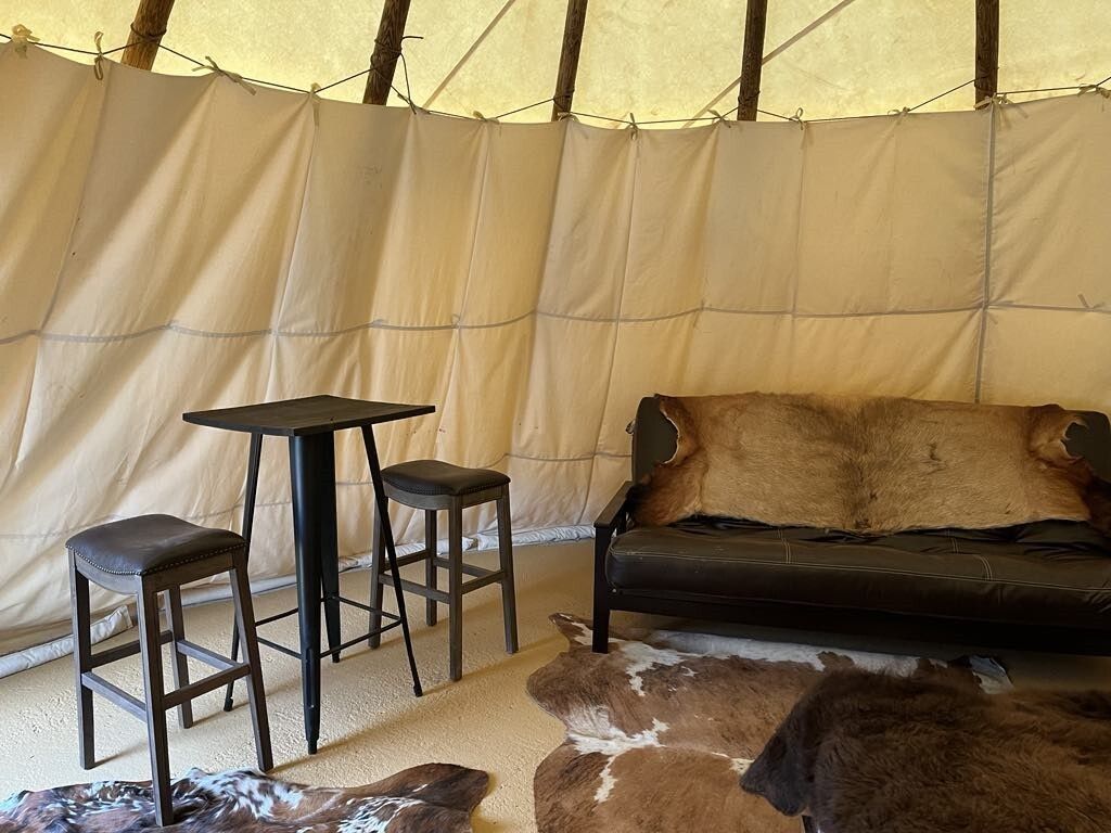 A living room with a couch , two tables and two stools.