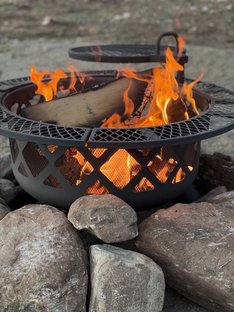 A fire pit is surrounded by rocks and is lit up