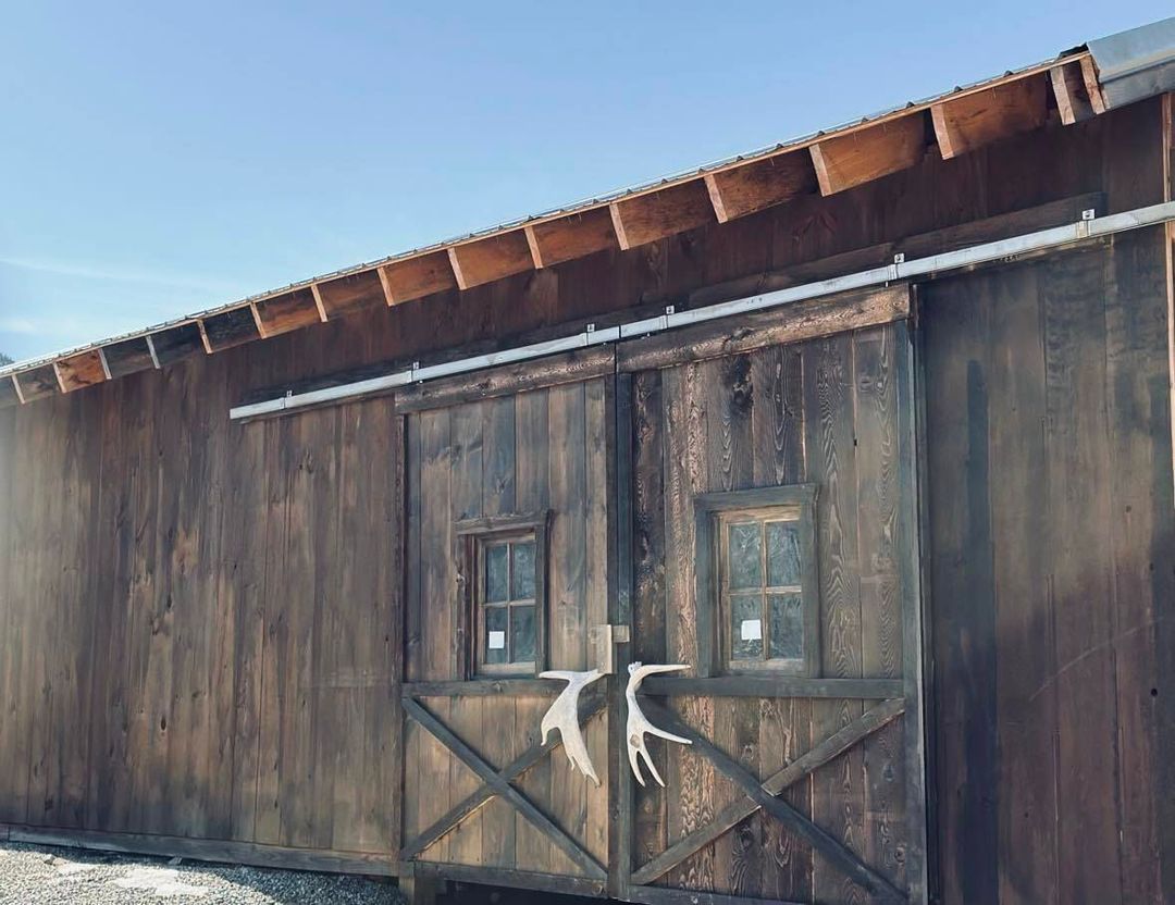 A wooden barn with a sliding barn door and two windows.