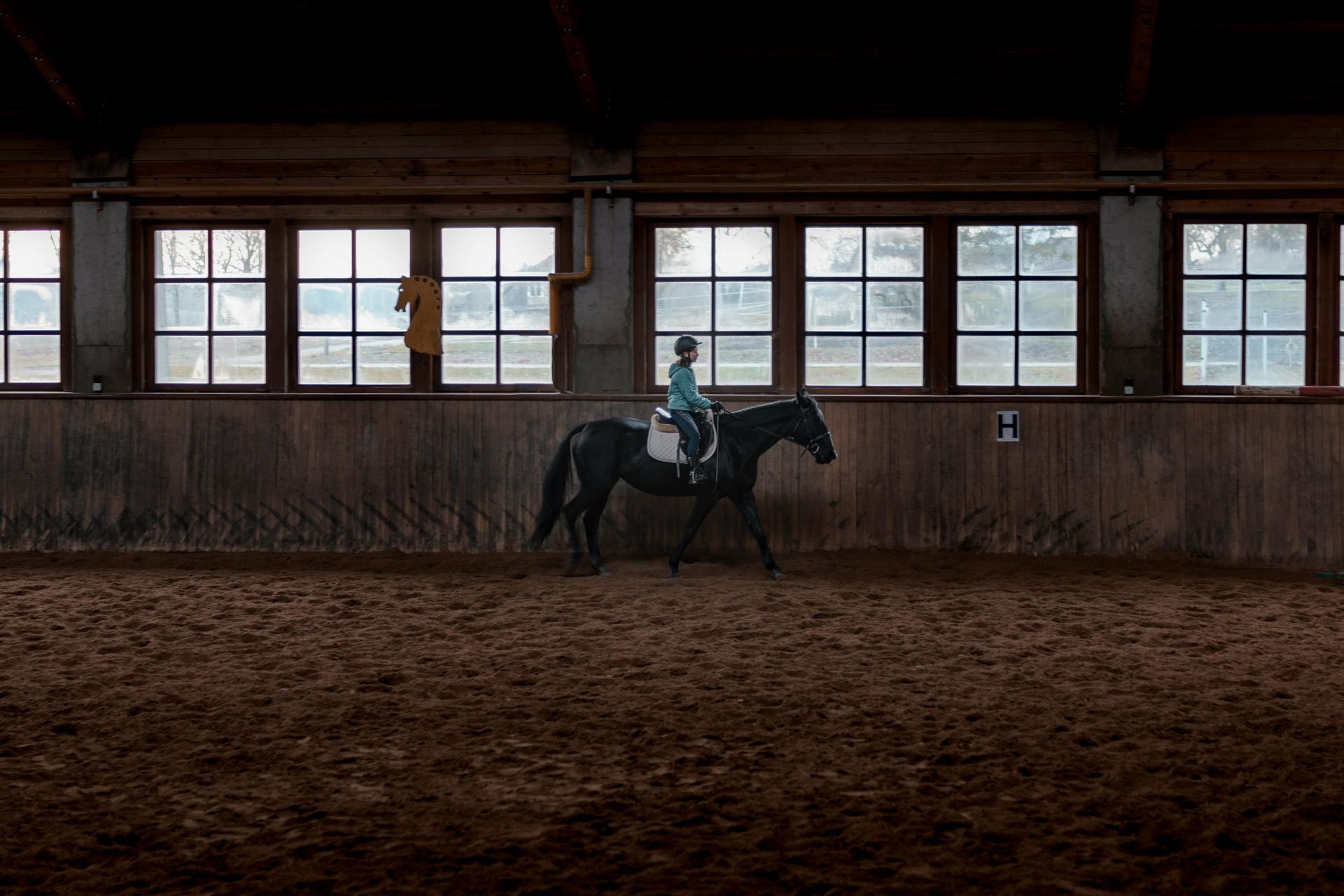 A person is riding a horse in an indoor arena.